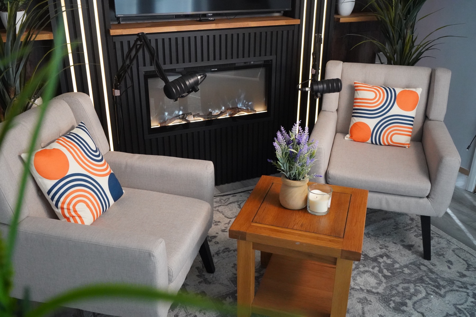 PodLot lounge area with armchairs, fireplace, plants, and microphones